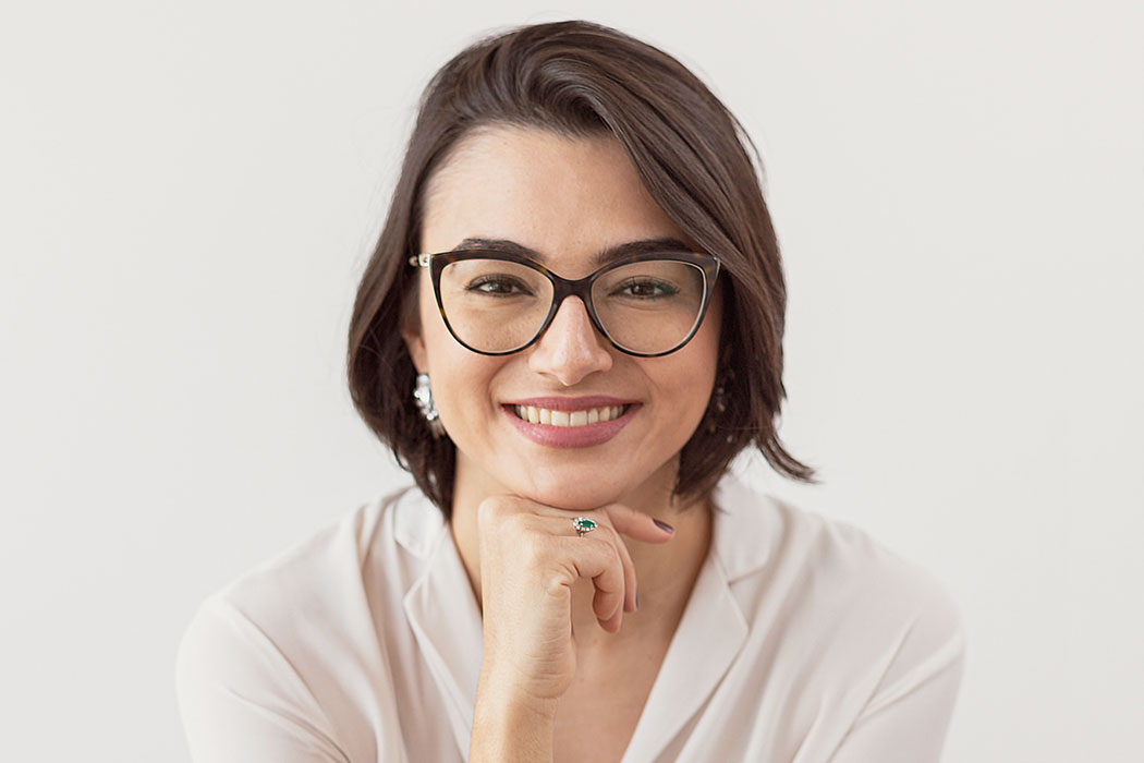 retrato da Dra Anne Brito sorrindo apoiaiando o queixo sobre a mão